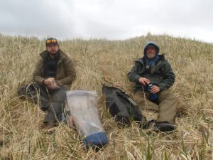 Reyce and Chris sit on small grassy hill, enjoying a lunch break