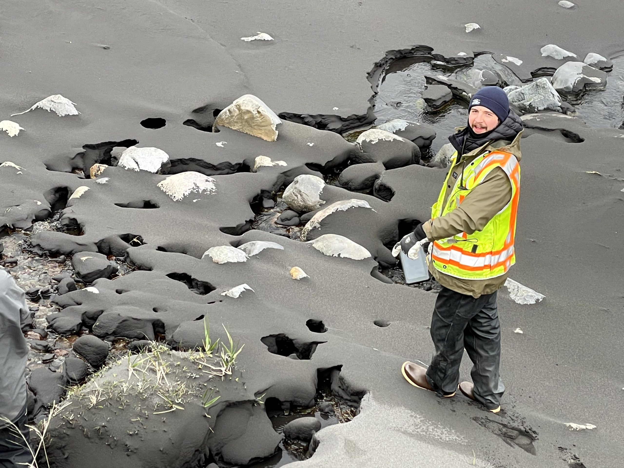Reyce is walking on a beach, looking up at the camera. Everything looks wet.