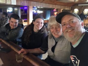 Four people sit at a bar smiling at the camera. 