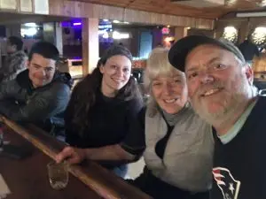 Four people sit at a bar smiling at the camera. 